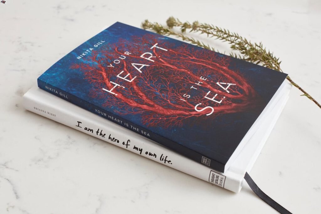 Close-up of two books stacked on a marble surface with a decorative branch.